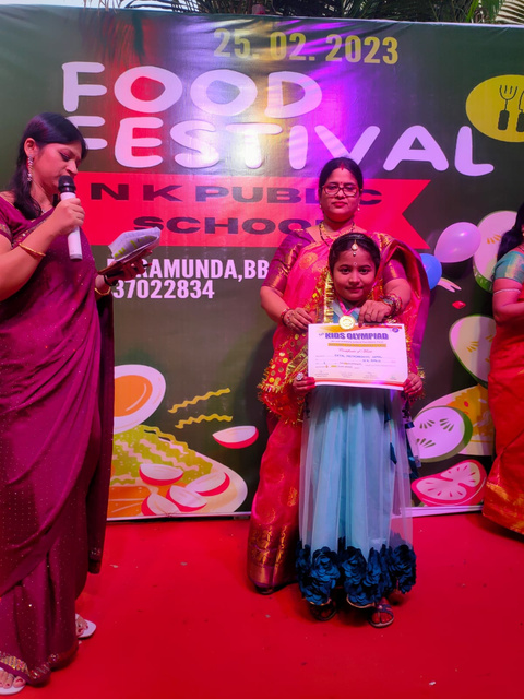 Prize distribution at N K Public School’s Food Festival. The image features students receiving awards for their culinary skills and contributions, celebrating their achievements and the vibrant food culture promoted by the school